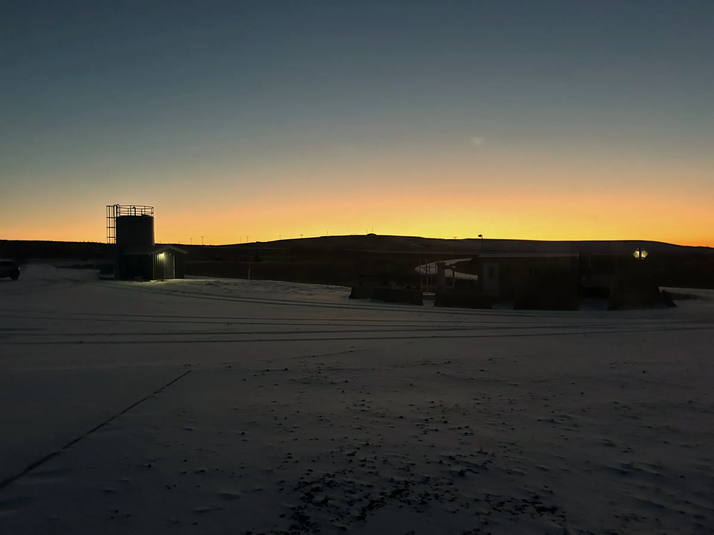 The Wyoming Innovation Center site at dusk, snow on the ground and an orange horizon.